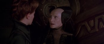 Movie still from “Dune” (1984), directed by David Lynch – An older woman wearing a black and gold costume; Close Up shot, Over the shoulder angle