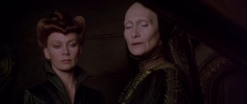 Movie still from “Dune” (1984), directed by David Lynch – A woman in a black and gold dress and another woman in a black dress; Close Up shot, Low angle
