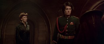 Movie still from “Dune” (1984), directed by David Lynch – A man in a military uniform standing in a dark room; Medium shot, Low angle