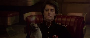 Movie still from “Dune” (1984), directed by David Lynch – A man in a military uniform sitting in a chair with a dog; Close Up shot, Over the shoulder angle