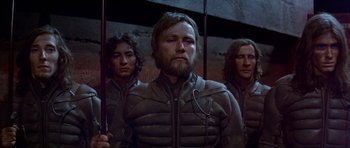 Movie still from “Dune” (1984), directed by David Lynch – A group of men standing next to each other in a room; Medium shot, Over the shoulder angle