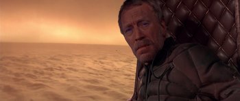 Movie still from “Dune” (1984), directed by David Lynch – An older man with headphones in front of a body of water; Close Up shot, Over the shoulder angle