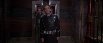 Movie still from “Dune” (1984), directed by David Lynch – A man in a uniform standing next to a woman; Medium shot, Low angle