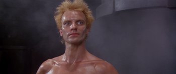 Movie still from “Dune” (1984), directed by David Lynch – A shirtless man with spiky blond hair and no shirt; Close Up shot, Low angle