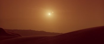 Movie still from “Dune” (1984), directed by David Lynch – The sun is setting over a desert landscape; Extreme Wide shot, Low angle