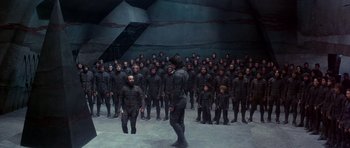 Movie still from “Dune” (1984), directed by David Lynch – A large group of people wearing black suits; Wide shot, High angle