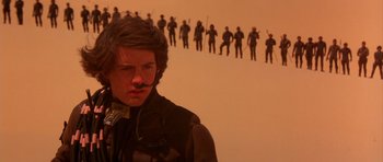 Movie still from “Dune” (1984), directed by David Lynch – A man with a mustache standing in front of a row of soldiers; Medium shot, Low angle