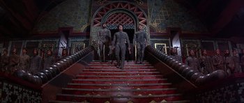 Movie still from “Dune” (1984), directed by David Lynch – A group of men in grey suits walking down a set of stairs; Wide shot, Low angle