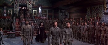 Movie still from “Dune” (1984), directed by David Lynch – A group of people standing next to each other in a room; Wide shot, High angle