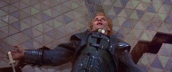Movie still from “Dune” (1984), directed by David Lynch – A man in a black suit is looking up at the ceiling; Medium shot, Overhead angle