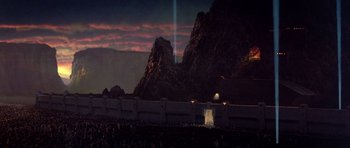 Movie still from “Dune” (1984), directed by David Lynch – A crowd of people standing in front of a mountain range at night; Extreme Wide shot, High angle