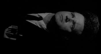 Movie still from “Eraserhead” (1977), directed by David Lynch – Black and white photograph of a man in a suit; Close Up shot, Low angle