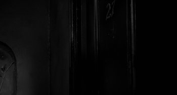 Movie still from “Eraserhead” (1977), directed by David Lynch – A dark room with a number 2 7 painted on the wall; Extreme Close Up shot, Low angle