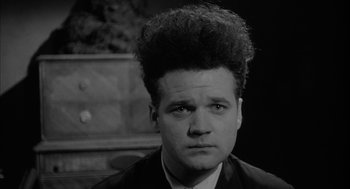 Movie still from “Eraserhead” (1977), directed by David Lynch – A black and white photo of a man with a weird hair style; Close Up shot, Low angle
