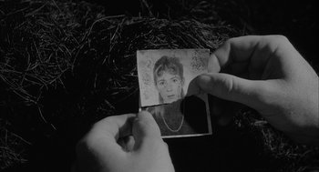 Movie still from “Eraserhead” (1977), directed by David Lynch – A black and white image of a person holding a photo; Close Up shot, High angle