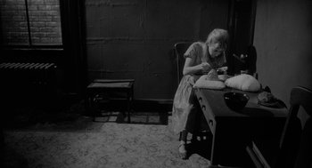 Movie still from “Eraserhead” (1977), directed by David Lynch – An older woman sitting at a table with a plate of food; Medium shot, High angle