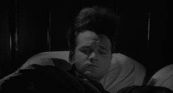 Movie still from “Eraserhead” (1977), directed by David Lynch – A black and white photo of a man laying in a bed; Close Up shot, High angle