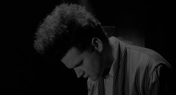 Movie still from “Eraserhead” (1977), directed by David Lynch – A young man is sitting down with his head down; Close Up shot, Low angle