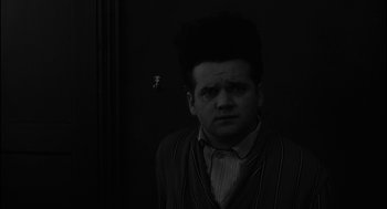 Movie still from “Eraserhead” (1977), directed by David Lynch – A black and white photo of a man with a strange hair style; Close Up shot, Over the shoulder angle