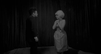 Movie still from “Eraserhead” (1977), directed by David Lynch – A man and a woman standing next to each other in front of a curtain; Medium shot, Over the shoulder angle
