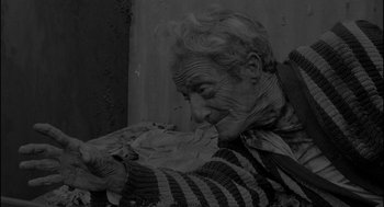 Movie still from “Eraserhead” (1977), directed by David Lynch – An old woman is eating a piece of food; Medium shot, Low angle