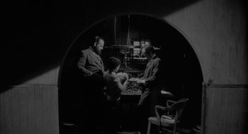 Movie still from “Eraserhead” (1977), directed by David Lynch – A group of people sitting around a table; Medium shot, High angle