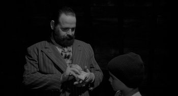 Movie still from “Eraserhead” (1977), directed by David Lynch – A man in a striped suit and a boy in a hat; Medium shot, Over the shoulder angle