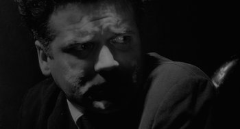 Movie still from “Eraserhead” (1977), directed by David Lynch – Black and white photograph of a man in a suit; Extreme Close Up shot, Over the shoulder angle