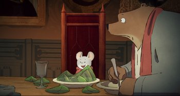 Movie still from “Ernest and Celestine: A Trip to Gibberitia” (2022), directed by Jean-Christophe Roger – A bear and a mouse are sitting in front of a plate of food on a table; Medium shot, High angle