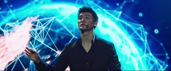 Movie still from “Escape Plan 2: Hades” (2018), directed by Steven C. Miller – A man with a headset in front of an abstract background; Medium shot, Low angle