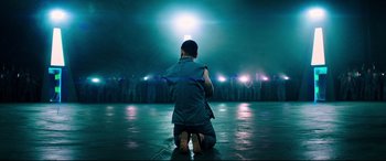 Movie still from “Escape Plan 2: Hades” (2018), directed by Steven C. Miller – A man kneeling on the ground in front of a group of people; Wide shot, High angle