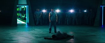 Movie still from “Escape Plan 2: Hades” (2018), directed by Steven C. Miller – A group of men standing around a man lying on the ground; Wide shot, High angle