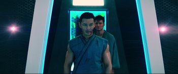 Movie still from “Escape Plan 2: Hades” (2018), directed by Steven C. Miller – A man standing next to another man in front of a wall; Medium shot, Over the shoulder angle