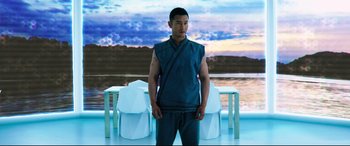 Movie still from “Escape Plan 2: Hades” (2018), directed by Steven C. Miller – A man standing in front of a table with a sky background; Medium shot, Low angle