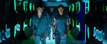 Movie still from “Escape Plan 2: Hades” (2018), directed by Steven C. Miller – A group of men walking down a hallway in a building; Medium shot, Low angle