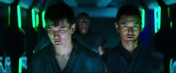 Movie still from “Escape Plan 2: Hades” (2018), directed by Steven C. Miller – A group of men standing next to each other in a dark room; Close Up shot, Low angle