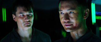 Movie still from “Escape Plan 2: Hades” (2018), directed by Steven C. Miller – A man and a woman standing next to each other in the dark; Close Up shot, Over the shoulder angle