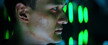 Movie still from “Escape Plan 2: Hades” (2018), directed by Steven C. Miller – A man's face in front of green lights; Close Up shot, Low angle