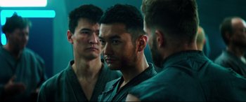 Movie still from “Escape Plan 2: Hades” (2018), directed by Steven C. Miller – A man looking at himself in the mirror while two other men look on; Close Up shot, Over the shoulder angle