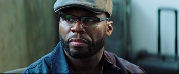 Movie still from “Escape Plan 2: Hades” (2018), directed by Steven C. Miller – A person wearing glasses and a hat; Close Up shot, Over the shoulder angle