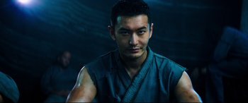 Movie still from “Escape Plan 2: Hades” (2018), directed by Steven C. Miller – A man in a blue shirt is posing for a picture; Close Up shot, Low angle