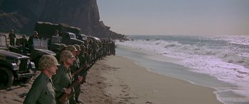 Movie still from “Escape from the Planet of the Apes” (1971), directed by Don Taylor – A group of people standing on a beach next to the ocean; Extreme Wide shot, High angle