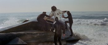 Movie still from “Escape from the Planet of the Apes” (1971), directed by Don Taylor – A group of people in wetsuits on a surfboard; Wide shot, High angle