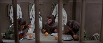 Movie still from “Escape from the Planet of the Apes” (1971), directed by Don Taylor – A group of people sitting at a table with plates of fruit; Medium shot, High angle