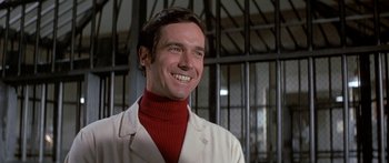 Movie still from “Escape from the Planet of the Apes” (1971), directed by Don Taylor – A man in a white lab coat and a red turtleneck smiling; Close Up shot, Low angle
