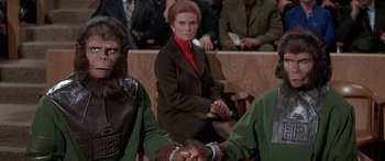 Movie still from “Escape from the Planet of the Apes” (1971), directed by Don Taylor – A woman sitting in front of a crowd of people; Medium shot, Over the shoulder angle
