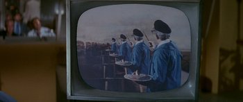Movie still from “Escape from the Planet of the Apes” (1971), directed by Don Taylor – A television screen showing a group of people holding trays of food; Medium shot, High angle