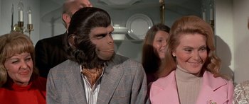 Movie still from “Escape from the Planet of the Apes” (1971), directed by Don Taylor – A man in a suit and a monkey mask; Close Up shot, Over the shoulder angle