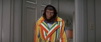Movie still from “Escape from the Planet of the Apes” (1971), directed by Don Taylor – A man dressed as a monkey in a colorful coat; Medium shot, Over the shoulder angle