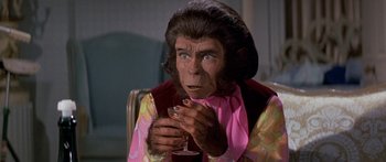 Movie still from “Escape from the Planet of the Apes” (1971), directed by Don Taylor – A man dressed like a monkey holding a glass of wine; Close Up shot, High angle